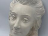 a white sculpture of a woman ' s head on a wall