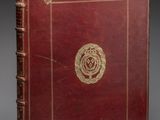 un vieux livre rouge avec un emblème doré sur la couverture