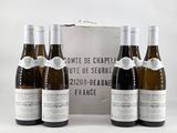 four bottles of wine are lined up in front of a silver box