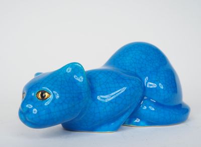 une figurine de chat bleu posée sur une surface blanche