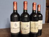 four bottles of wine are lined up on a wooden table