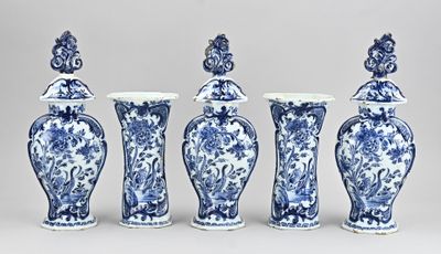 quatre vases bleus et blancs sont alignés sur un fond gris