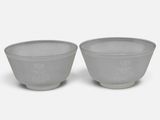 pair of gray bowls with white designs on them on a white surface