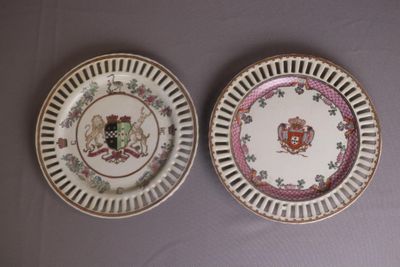 two plates with a coat of arms on them sitting on a table