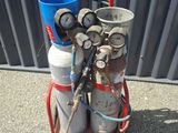 a red cart with two cylinders and a blue bucket on it
