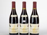 trois bouteilles de vin rouge sont posées sur une surface blanche