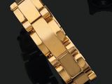 gros plan d'un bracelet en or sur une surface noire
