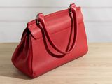 a red handbag sitting on top of a wooden table