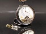 une montre de poche en argent posée sur une table, attachée à une chaîne