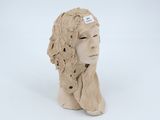 a close up of a clay sculpture of a woman ' s head on a white surface