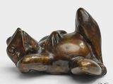 une photo d'une sculpture en bronze représentant un chat couché sur le dos