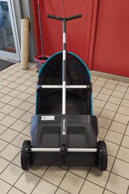 a black and blue stroller on the floor in front of a red wall