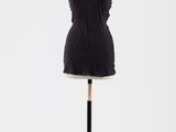 une robe noire posée sur un mannequin, sur fond blanc