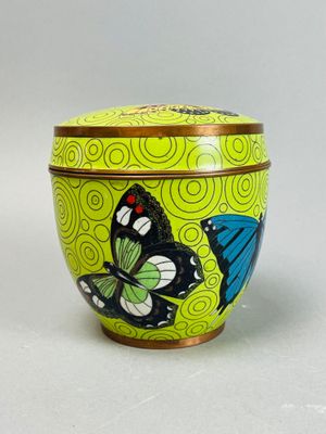boîte en forme de papillon jaune et bleu avec couvercle, posée sur une surface blanche