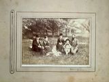 an old photo of a group of people sitting in the grass