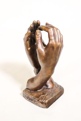 statue en bronze représentant une main tenant un téléphone portable posée sur une surface blanche