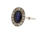 gros plan d'une bague avec une pierre bleue entourée de diamants