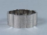 une photo en gros plan d'un bracelet en argent posé sur une surface blanche