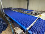un tapis roulant bleu dans un entrepôt, recouvert d'une bâche bleue