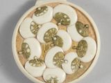 a picture of a white and gold broochle with green and white buttons