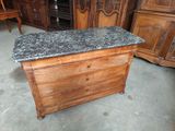 a wooden chest with a granite top in the middle of a room