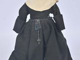 an image of a doll of a woman in a black dress and a nun ' s hat