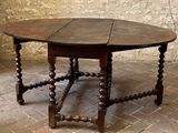 a wooden table with a circular top on a brick floor