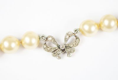 an image of a necklace with pearls and a bow on it