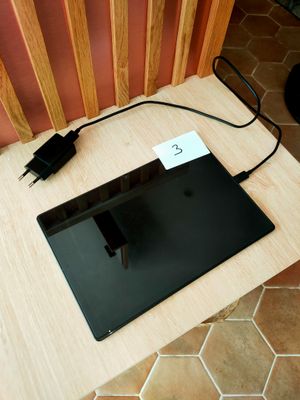 un ordinateur portable posé sur une table, avec un chargeur branché dessus