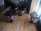 tables and chairs in a room with a large painting on the wall