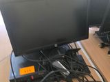 deux écrans d'ordinateur posés sur un bureau, entourés de câbles