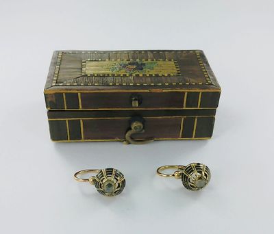une image représentant une boîte en bois avec deux bagues et une paire de boucles d'oreilles