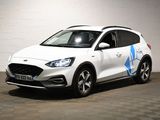 La voiture blanche est garée dans le garage ; elle porte un autocollant bleu sur le côté.