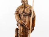 wooden statue of a man with a staff and a dog