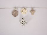 three silver pendants and a silver coin on a string