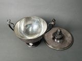 a silver bowl with a lid on a gray surface