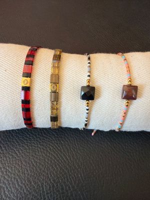 three different bracelets on a white napkin on a black leather surface