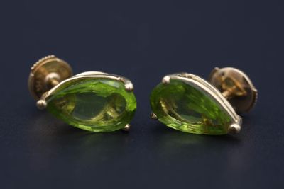 une paire de boucles d'oreilles en verre vert posées sur une surface noire