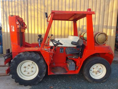 un petit tracteur rouge garé devant un bâtiment