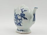 a small blue and white teapot with flowers on it