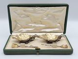 two silver spoons in a green case on a white surface