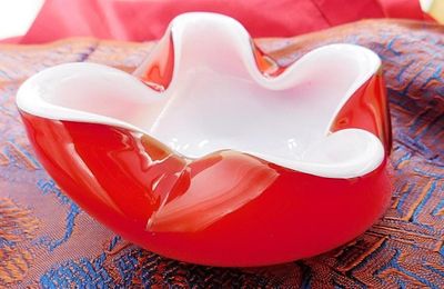 un bol rouge contenant une fleur blanche, posé sur une table