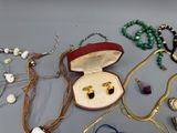 de nombreux bijoux posés sur une table, à côté d'un écrin rouge