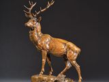 une sculpture en bronze représentant un cerf debout au sommet d'un rocher