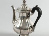 an antique silver teapot with a black handle on a white background