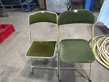 two green chairs sitting next to each other in a warehouse