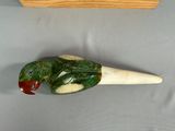 a green and red bird sitting on top of a piece of wood