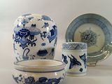 a blue and white vase and two cups on a table