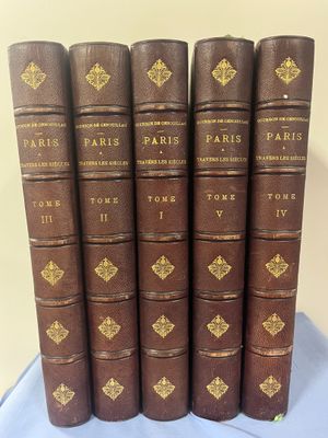 six vieux livres sont alignés sur une nappe bleue