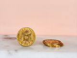 two gold coins sitting next to each other on top of a marble counter